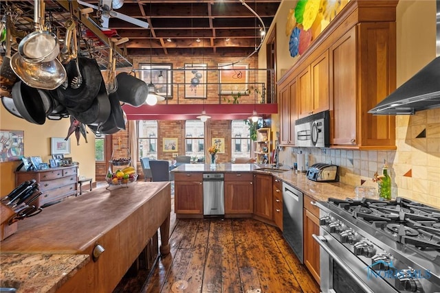 1 S Saint Clair St, Toledo, OH 43604 - kitchen with stainless steel appliances, a peninsula, wall chimney exhaust hood, and brown cabinetry