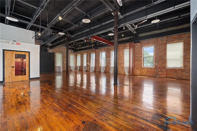 1 S Saint Clair St, Toledo, OH 43604 - misc room with hardwood / wood-style floors, brick wall, a towering ceiling, and baseboards