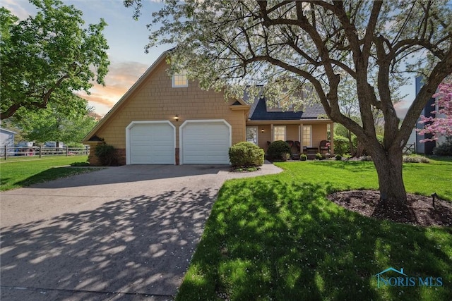 view of front of home with fence, a yard, and concrete driveway