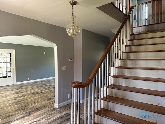 940 N Main St, Fostoria, OH 44830 - staircase featuring wood finished floors, baseboards, arched walkways, and a chandelier