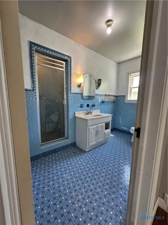 940 N Main St, Fostoria, OH 44830 - bathroom featuring tile walls, vanity, toilet, and a wainscoted wall