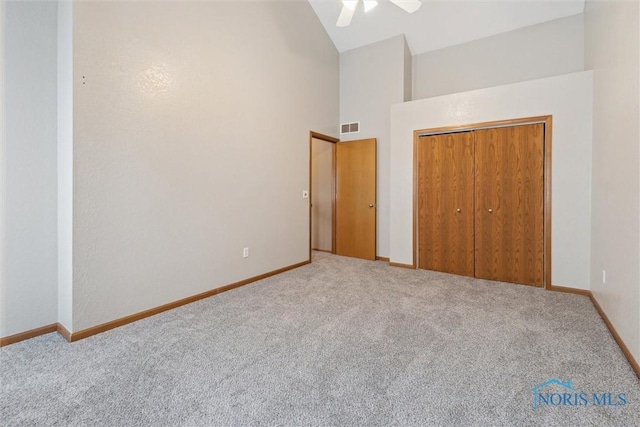 unfurnished bedroom with high vaulted ceiling, baseboards, carpet, and visible vents