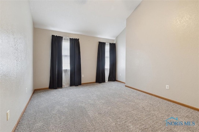 carpeted empty room with baseboards and lofted ceiling