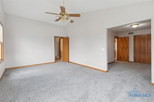 carpeted spare room with baseboards, a ceiling fan, visible vents, and lofted ceiling