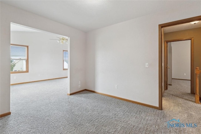 carpeted empty room featuring baseboards and a ceiling fan