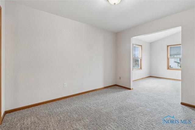 carpeted empty room featuring baseboards