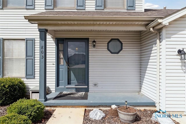 property entrance with a shingled roof and covered porch
