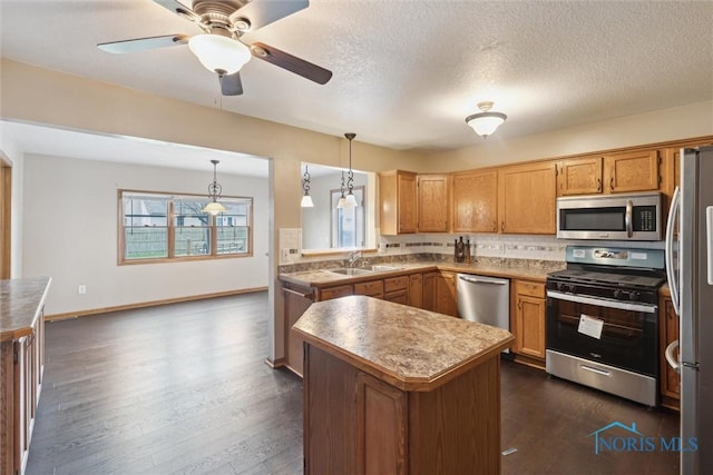 kitchen with a center island, a sink, dark wood-style floors, stainless steel appliances, and decorative backsplash