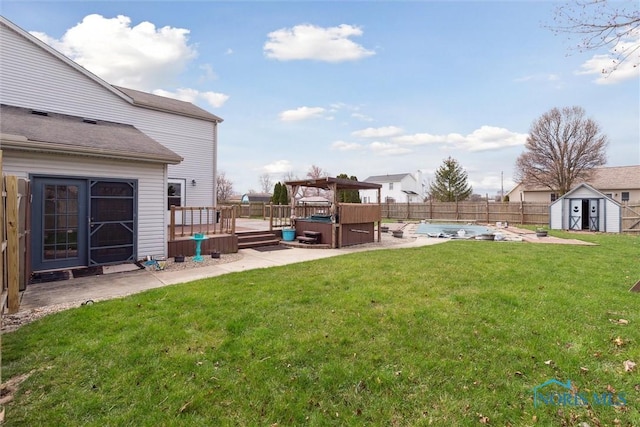 view of yard with an outdoor structure, a patio area, a fenced backyard, a deck, and a storage unit