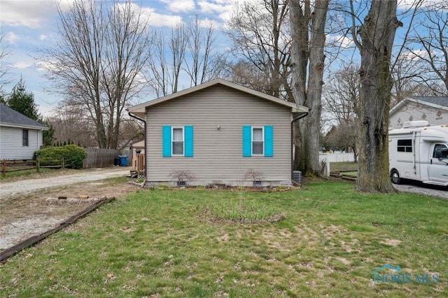view of home's exterior with a yard, crawl space, fence, and dirt driveway