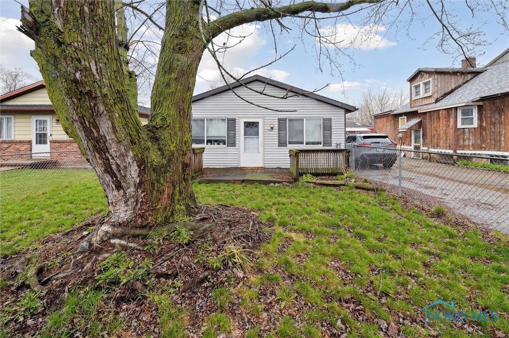 view of front of property featuring driveway, fence, and a front lawn