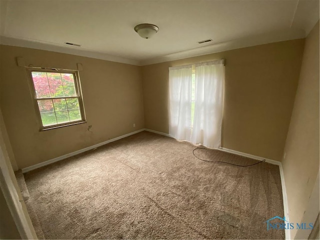 unfurnished room featuring baseboards, visible vents, and carpet