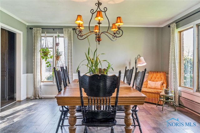 dining area with baseboards, ornamental molding, a notable chandelier, and hardwood / wood-style flooring