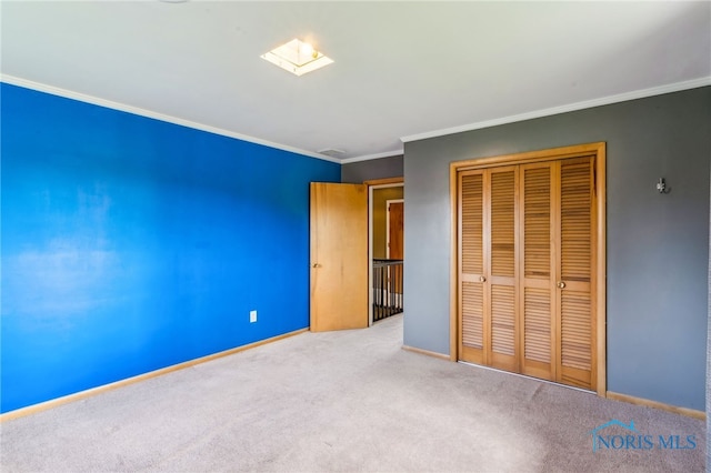 unfurnished bedroom with a closet, crown molding, baseboards, and carpet floors