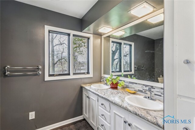 full bath with double vanity, a sink, and tasteful backsplash