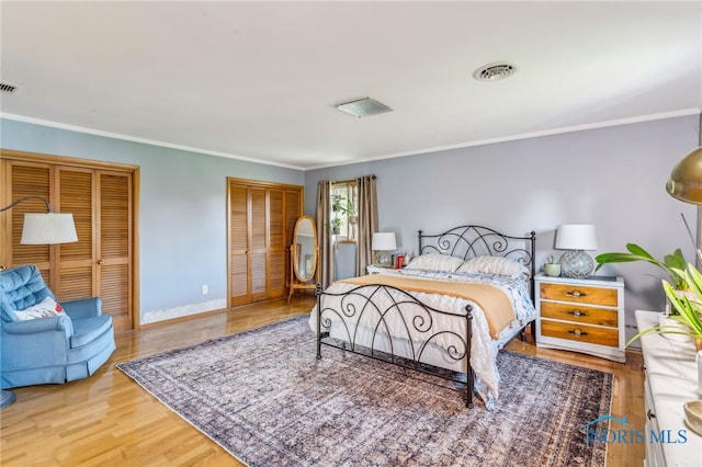 bedroom with crown molding, baseboards, multiple closets, and wood finished floors