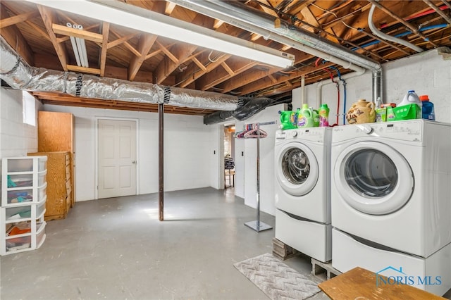 washroom featuring concrete block wall, laundry area, and washing machine and clothes dryer