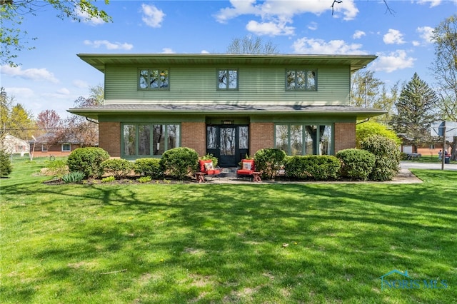 rear view of property featuring a yard and brick siding