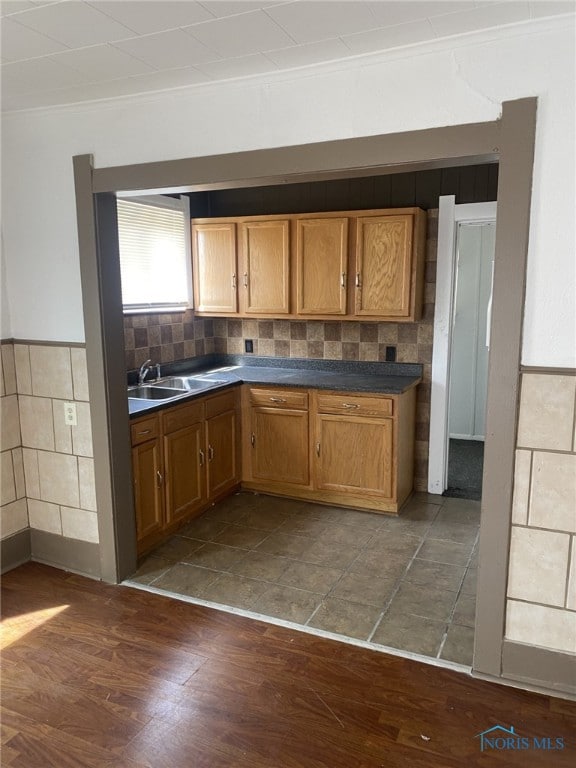 734 Parker Ave, Toledo, OH 43605 - kitchen with brown cabinets, dark countertops, a sink, tile walls, and dark wood-style flooring