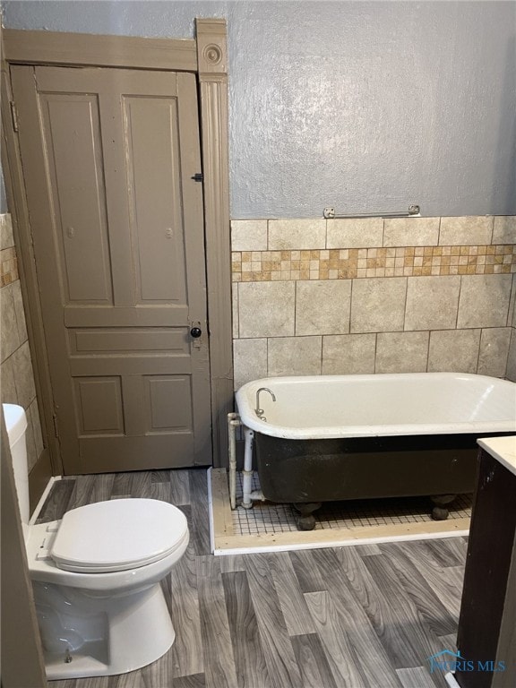 734 Parker Ave, Toledo, OH 43605 - full bathroom with toilet, a freestanding tub, wood finished floors, and tile walls