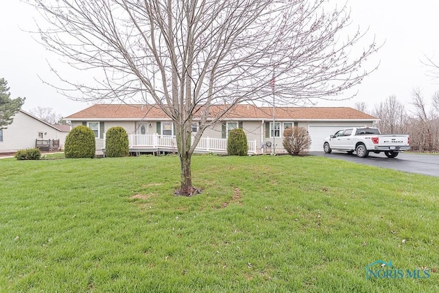 single story home with an attached garage, a front lawn, and aphalt driveway