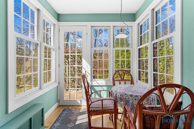 sunroom / solarium featuring baseboards, radiator, and wood finished floors