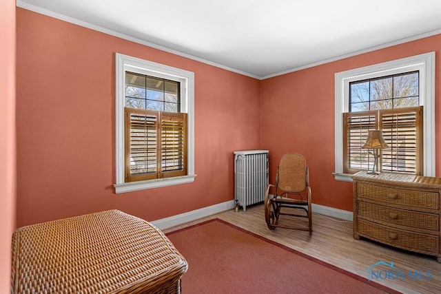 bedroom featuring wood finished floors, radiator heating unit, baseboards, and multiple windows