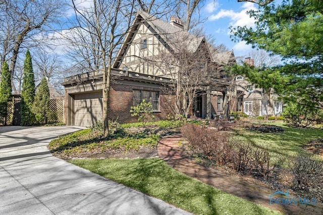 view of front of home with an attached garage, a chimney, driveway, and brick siding