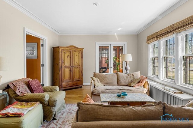 living area with light wood-style floors, french doors, radiator, and crown molding