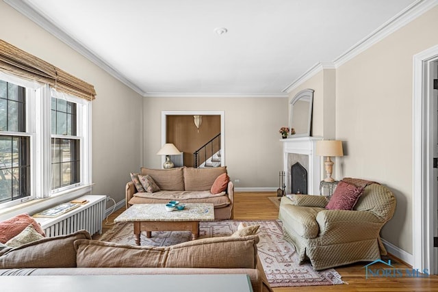 living room featuring baseboards, a fireplace, stairway, crown molding, and wood finished floors