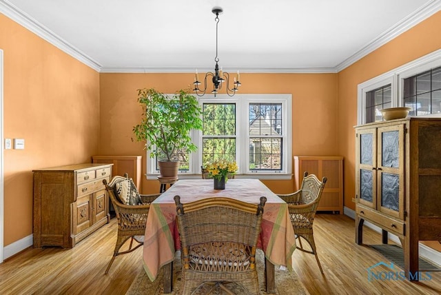 dining space featuring light wood-style floors, an inviting chandelier, and crown molding