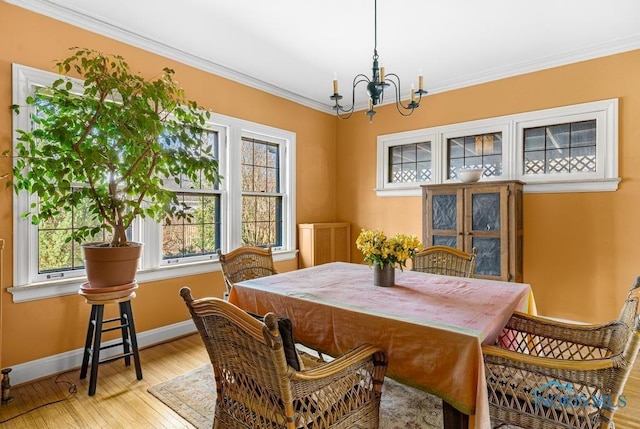 dining space with an inviting chandelier, ornamental molding, hardwood / wood-style flooring, and a wealth of natural light