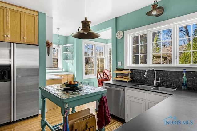 kitchen featuring tasteful backsplash, a sink, dark countertops, stainless steel appliances, and pendant lighting