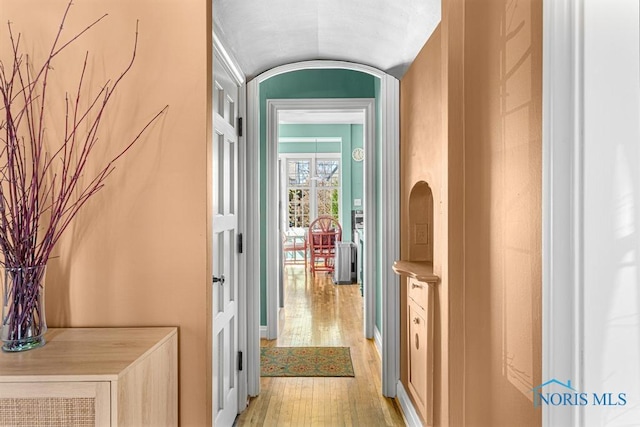 hall with light wood-style flooring and vaulted ceiling