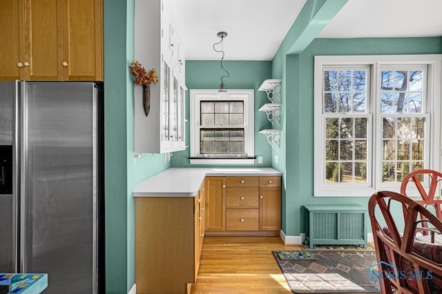 kitchen with light wood-style floors, radiator heating unit, stainless steel fridge with ice dispenser, and a wealth of natural light
