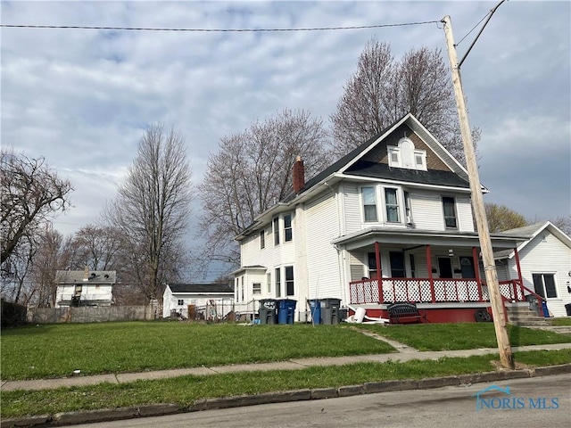 view of front of home with a front lawn, covered porch, and a chimney