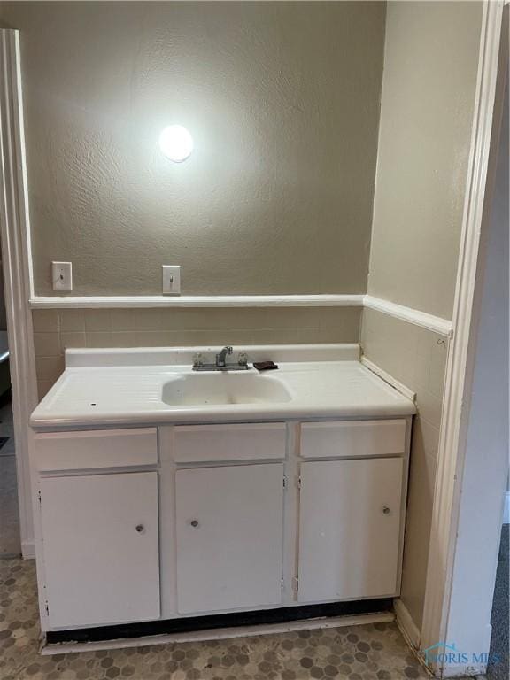 bathroom with a textured wall and vanity