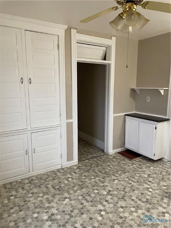 kitchen with baseboards, white cabinetry, and a ceiling fan