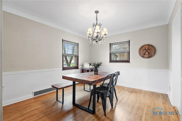 dining space with a notable chandelier, visible vents, baseboards, and wood finished floors