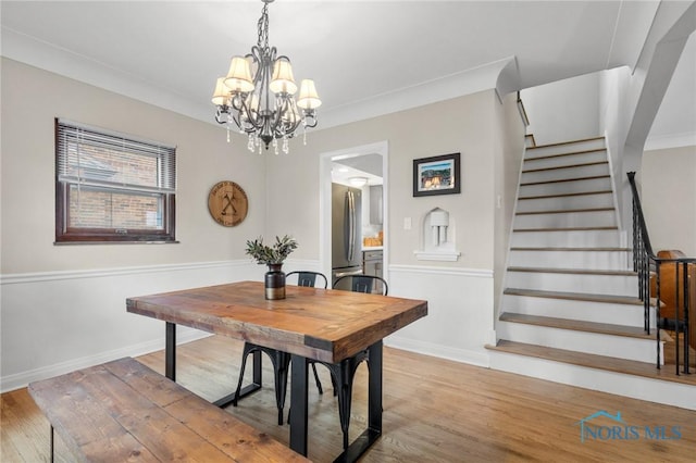 dining area with stairway, baseboards, an inviting chandelier, and wood finished floors