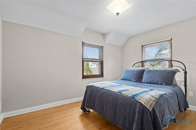 bedroom with multiple windows, baseboards, and wood finished floors