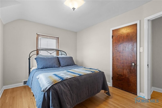 bedroom with visible vents, baseboards, light wood-style floors, and lofted ceiling