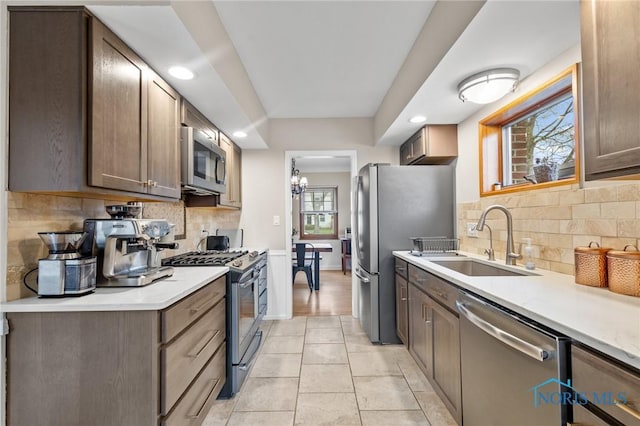 kitchen with decorative backsplash, light countertops, a sink, and appliances with stainless steel finishes