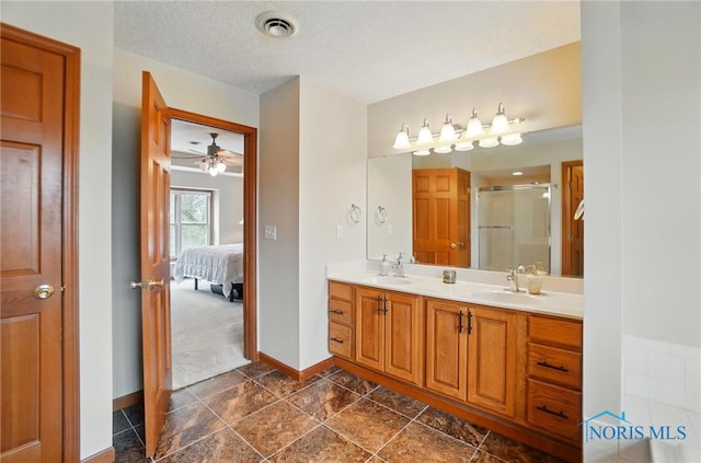 full bath with visible vents, a sink, a stall shower, double vanity, and baseboards