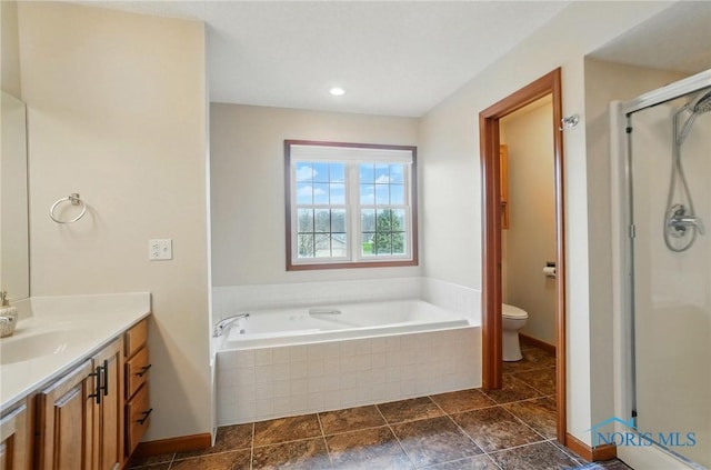 bathroom with baseboards, toilet, vanity, a stall shower, and a garden tub