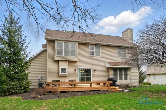 rear view of property with a yard, a wooden deck, and a chimney