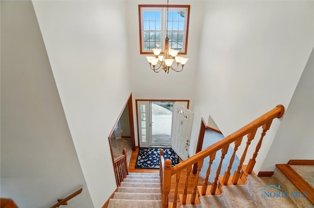 entrance foyer featuring stairs, a towering ceiling, and an inviting chandelier