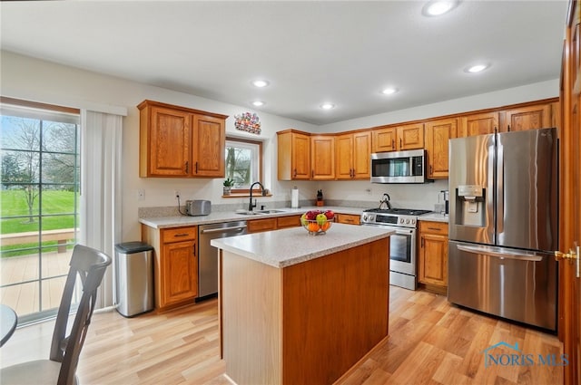 kitchen with a wealth of natural light, appliances with stainless steel finishes, light countertops, a sink, and light wood finished floors