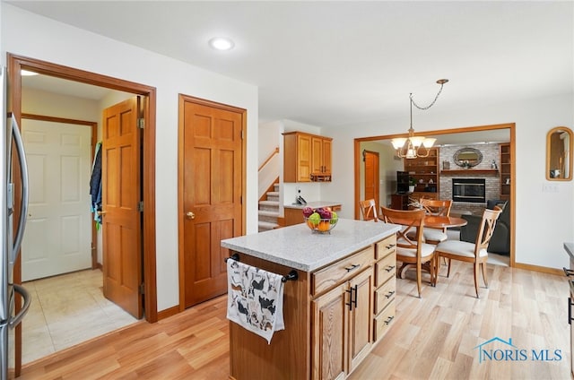 kitchen with pendant lighting, an inviting chandelier, a center island, light wood finished floors, and baseboards