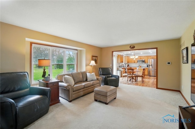 living area with a chandelier, light colored carpet, and baseboards